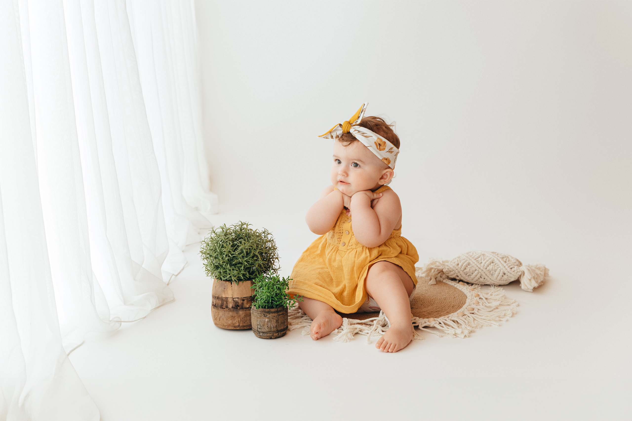 Sitzendes Kind mit kleiner Pflanze neben dran. Bei einem Fotoshooting